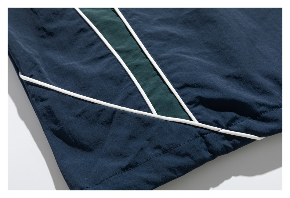 Close-up of a dark navy garment hem with white piping and a dark green inset panel.