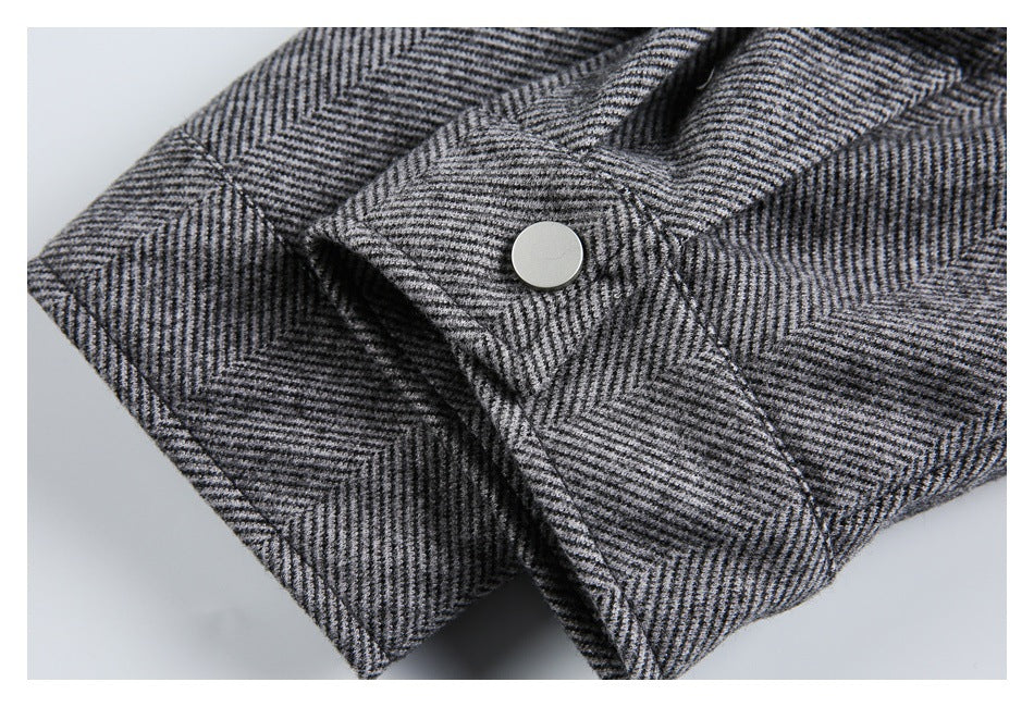 Close-up of a gray herringbone jacket cuff with a round metal snap.