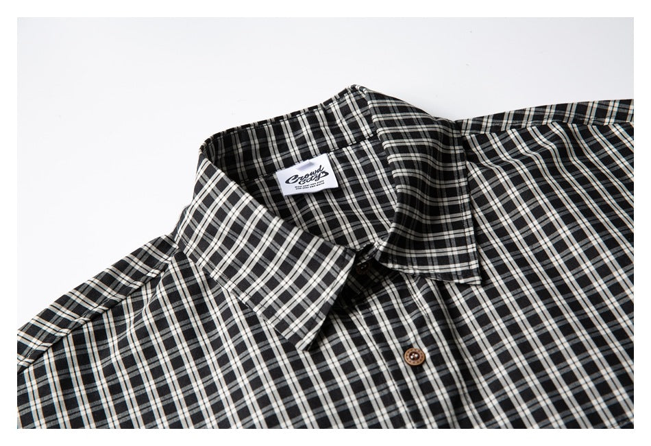 Close-up of a black-and-white plaid shirt collar, neckline, and brown buttons.