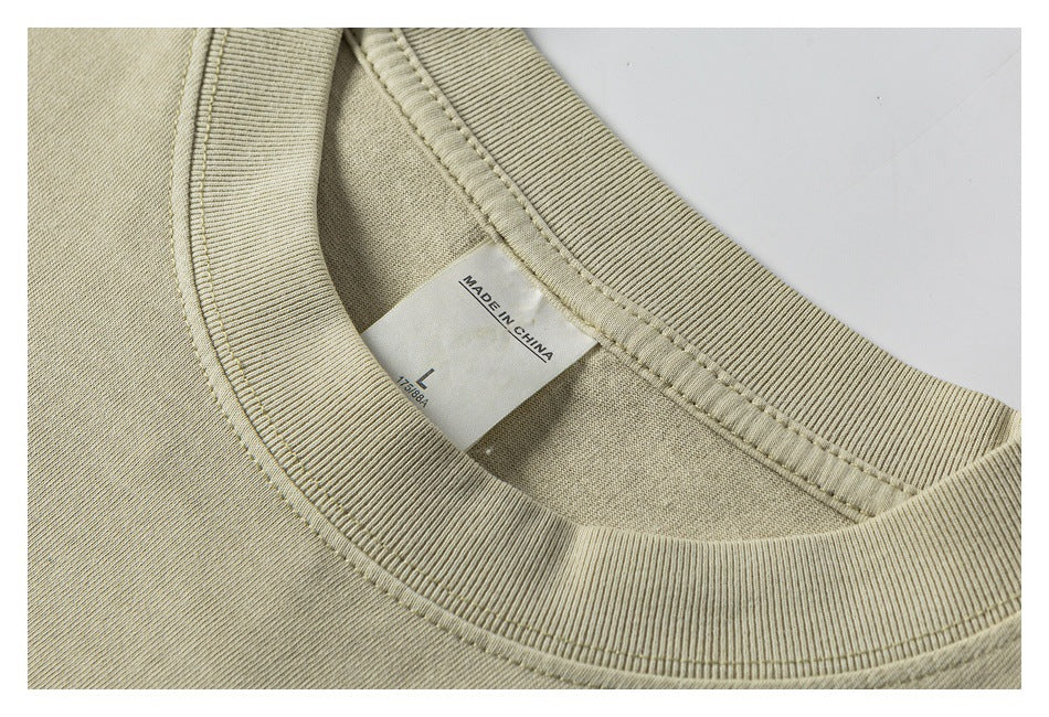 Close-up of a cream T-shirt's ribbed crew neckline and inner label marked size L and Made in China.