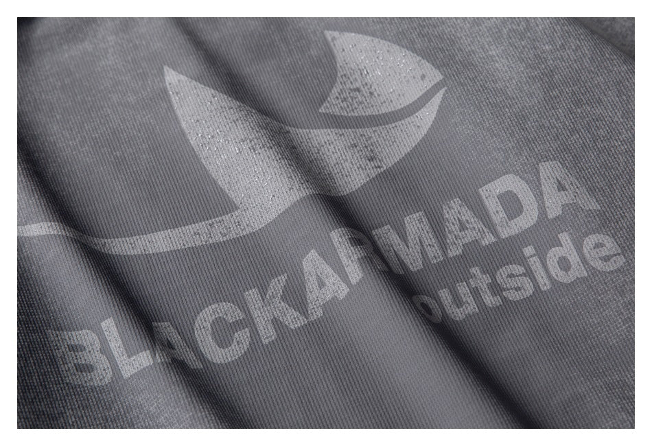 Close-up of a silver BLACKARMADA outside logo printed on gray garment fabric.