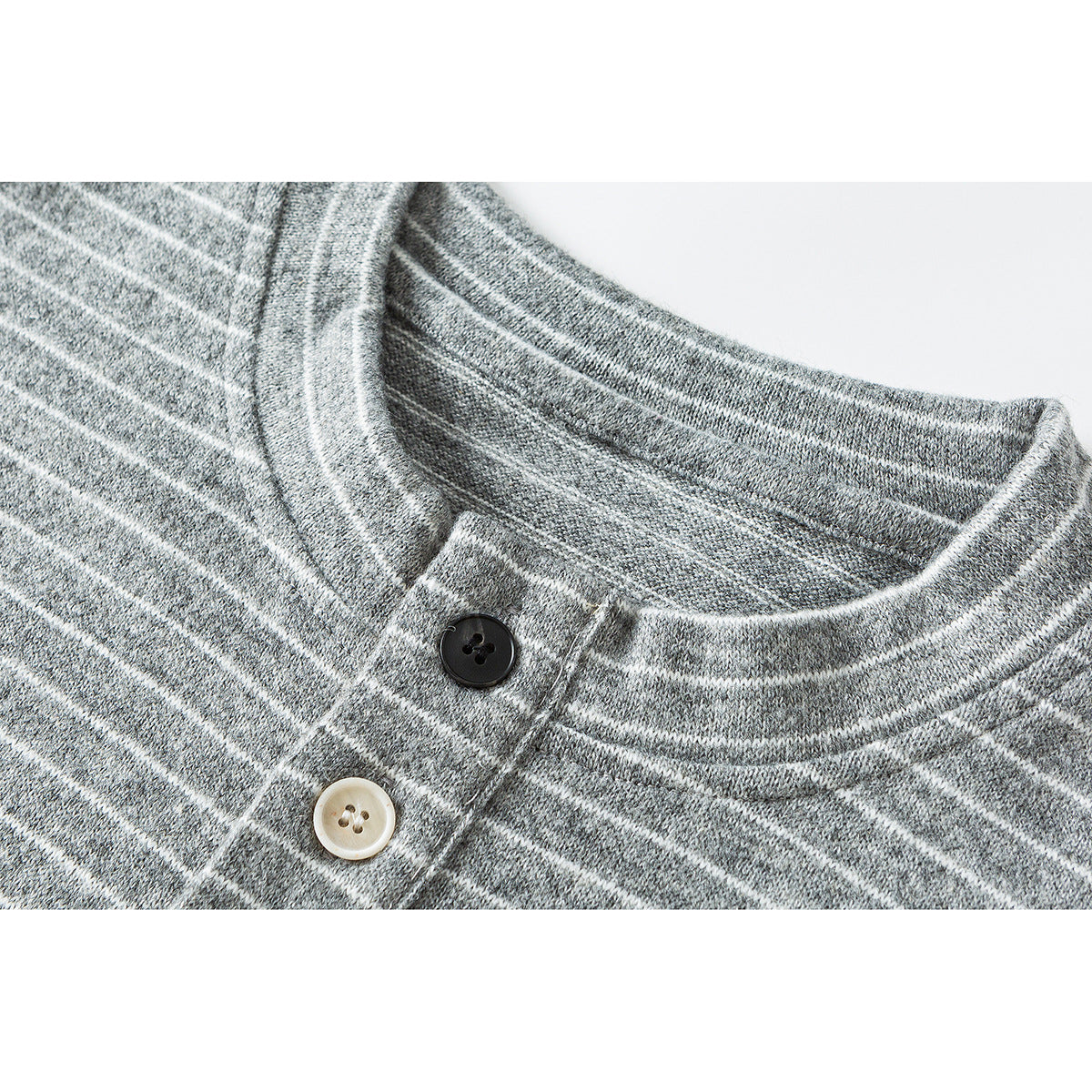 Close-up of a gray knit shirt with thin white stripes, a banded neckline and contrasting two-button placket.