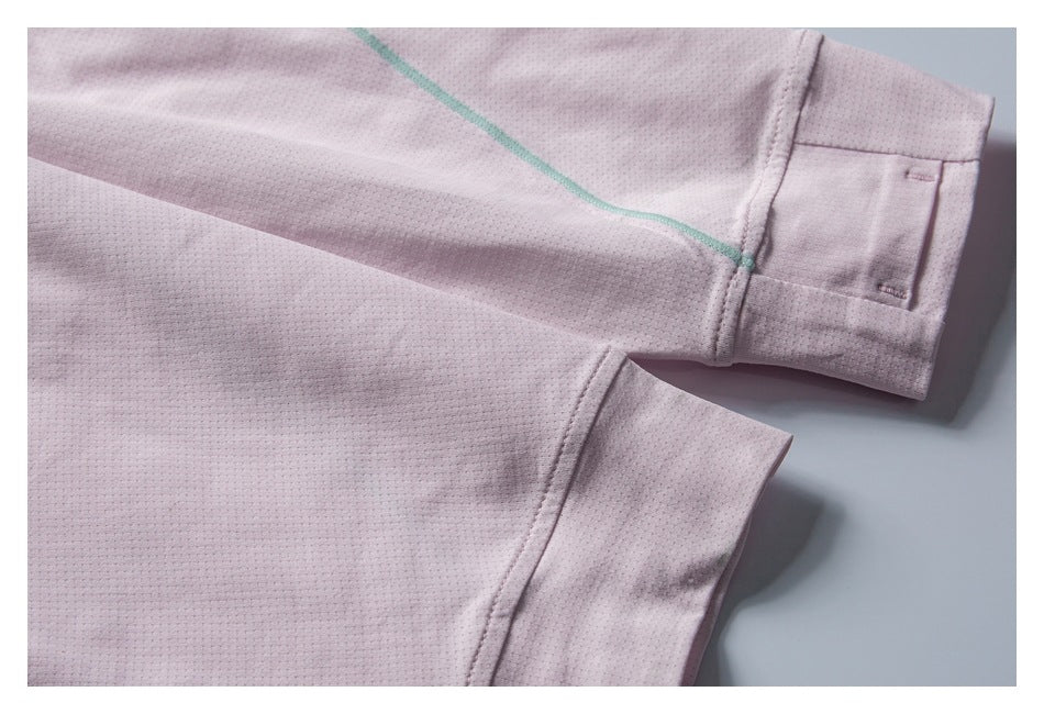 Close-up of pale pink garment sleeves and cuffs, showing mint-green seam piping and stitched details.