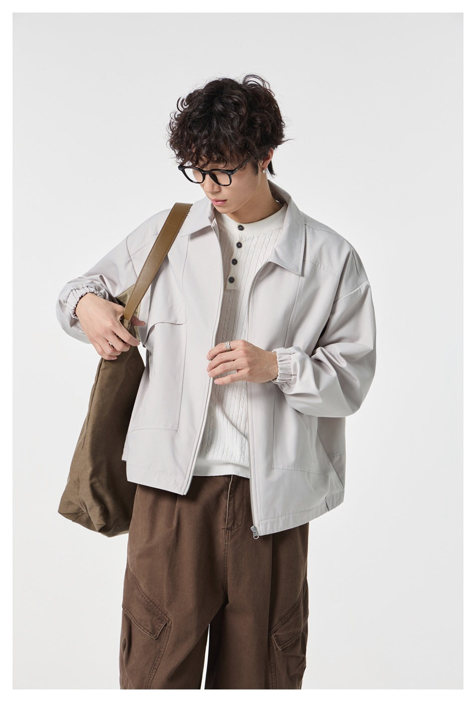 Closer view of a model wearing a light gray zip-front jacket with a pointed collar and large pockets.