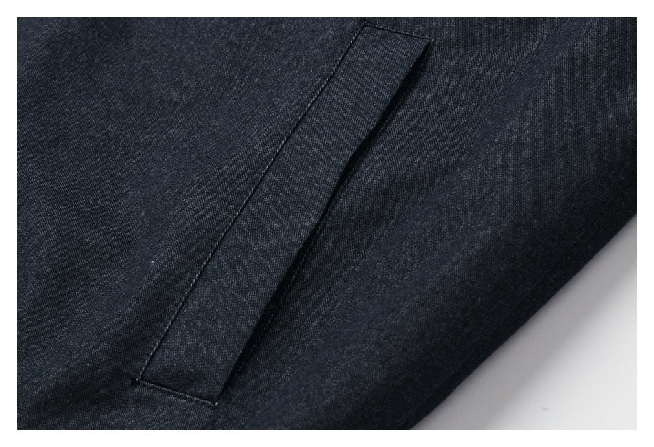 Close-up of a dark jacket's narrow vertical welt pocket and stitched panel.