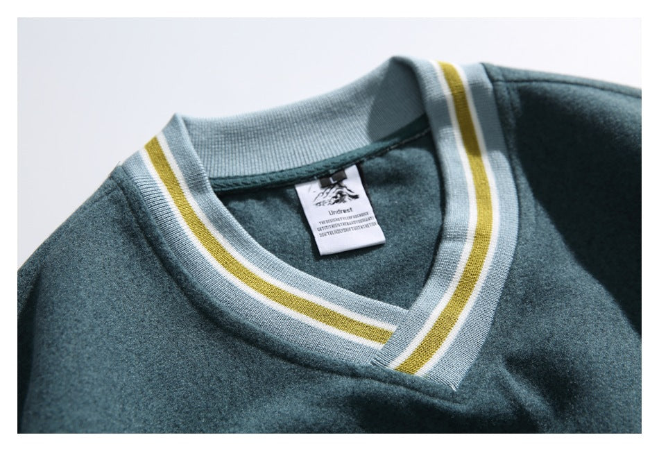 Close-up of a dark teal sweatshirt's striped V-neck ribbing and sewn-in neck label.
