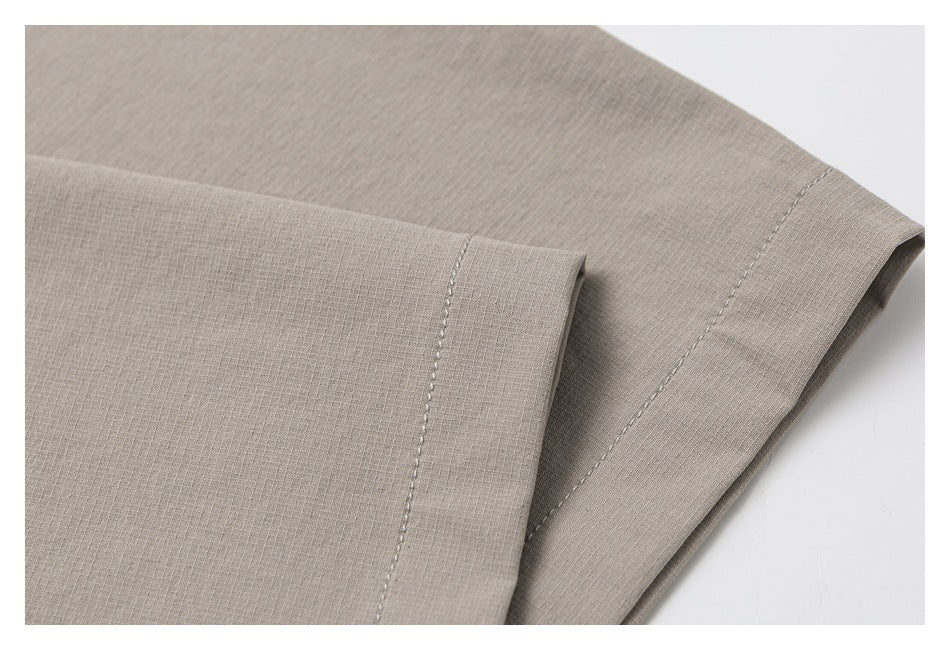 Close-up of the cuff and sleeve seam on a light taupe shirt.