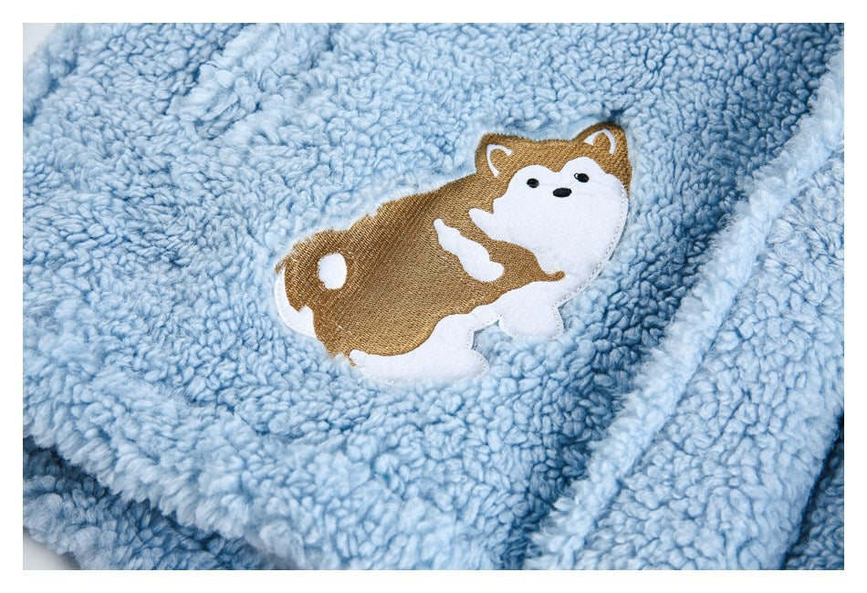 Close-up of a brown-and-white dog applique on pale blue plush fabric.