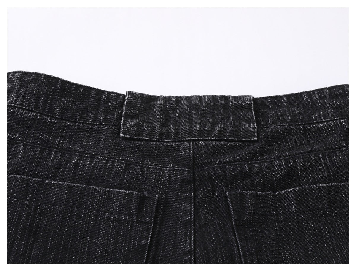 Close-up of the black jeans' back waistband, belt loop, yoke seam, and upper pocket edges.