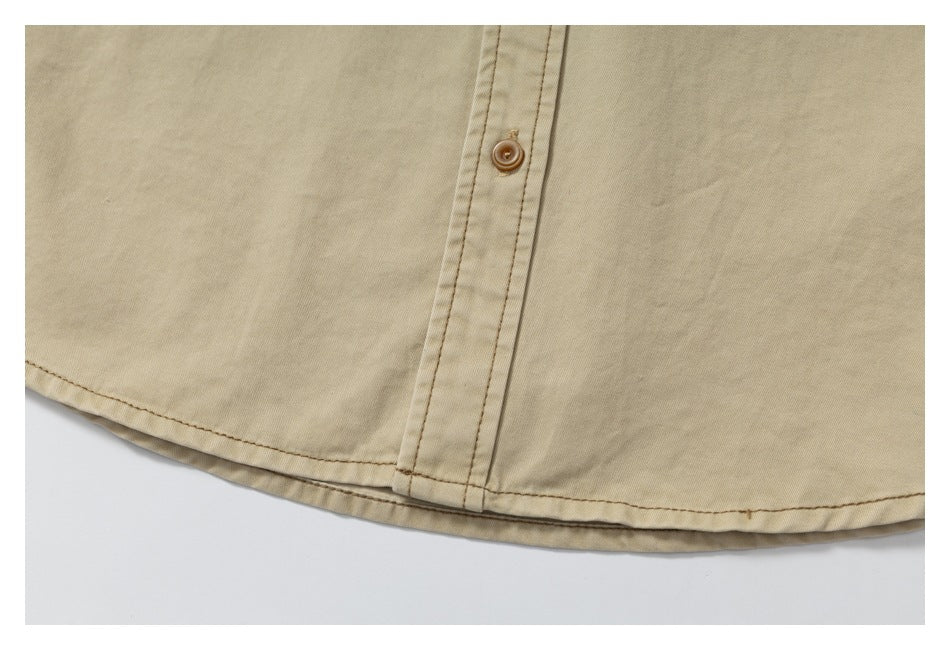 Close-up of a tan garment hem and button placket with brown topstitching.