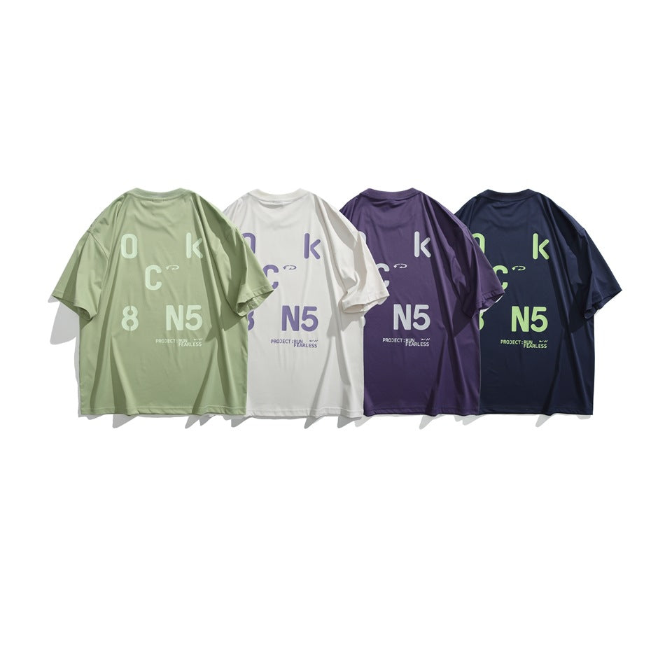 Four oversized graphic T-shirts shown from the back in sage green, white, purple, and navy.