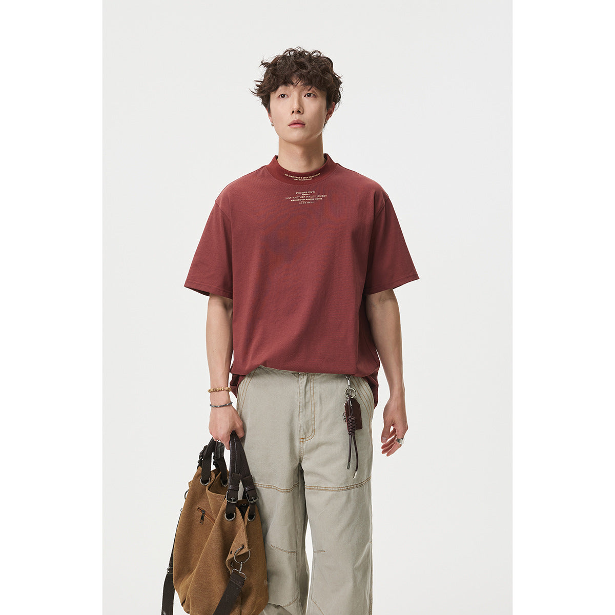 Model wearing a loose burgundy short-sleeve T-shirt with small chest text, shown from the front.