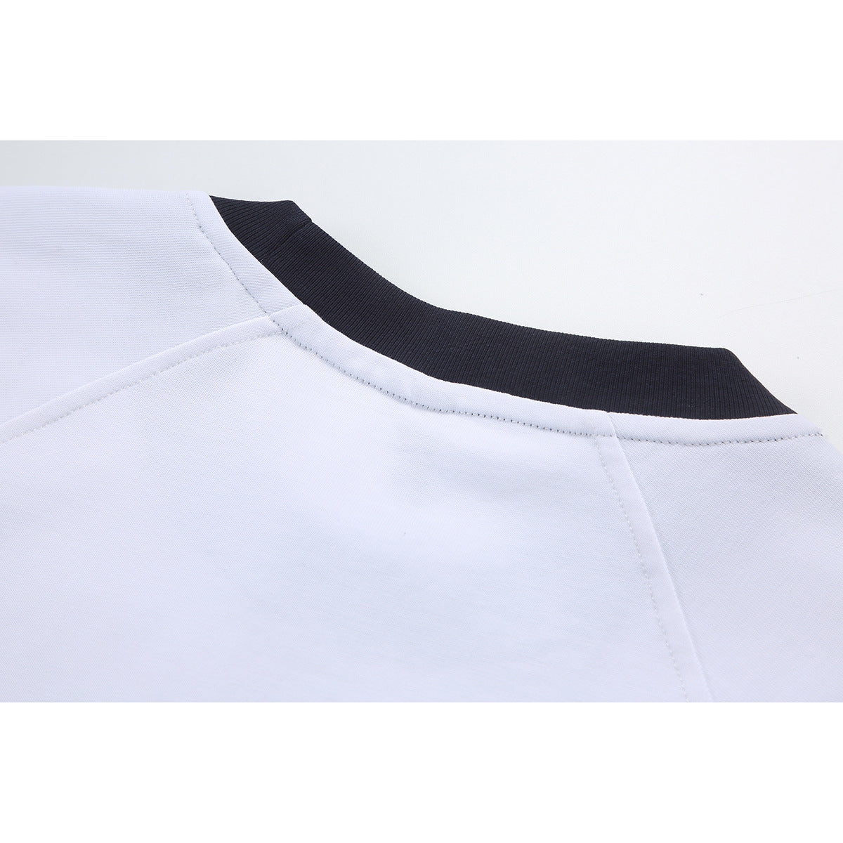 Close-up of a white shirt's neckline with a contrasting dark ribbed collar and visible shoulder seams.
