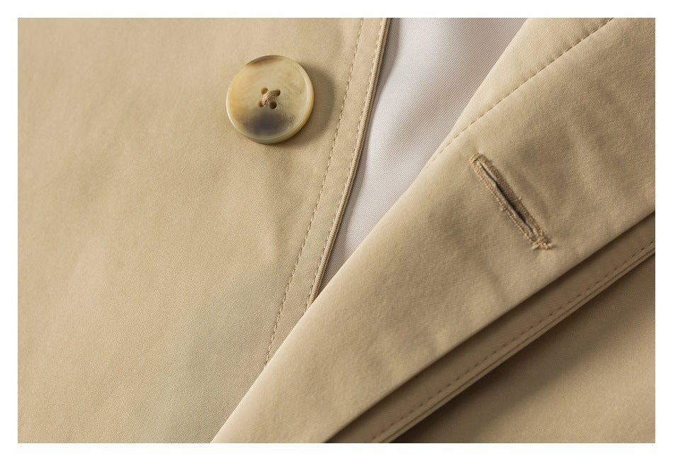 Close-up of a beige garment showing a round button, lapel buttonhole, and pale lining.