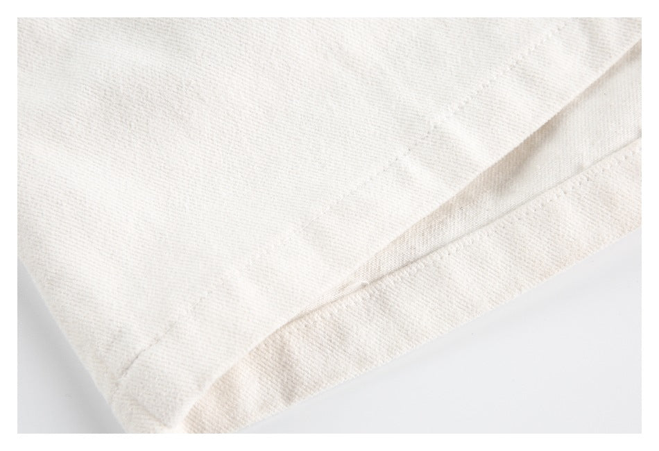 Close-up of a double-stitched folded hem on an ivory garment.