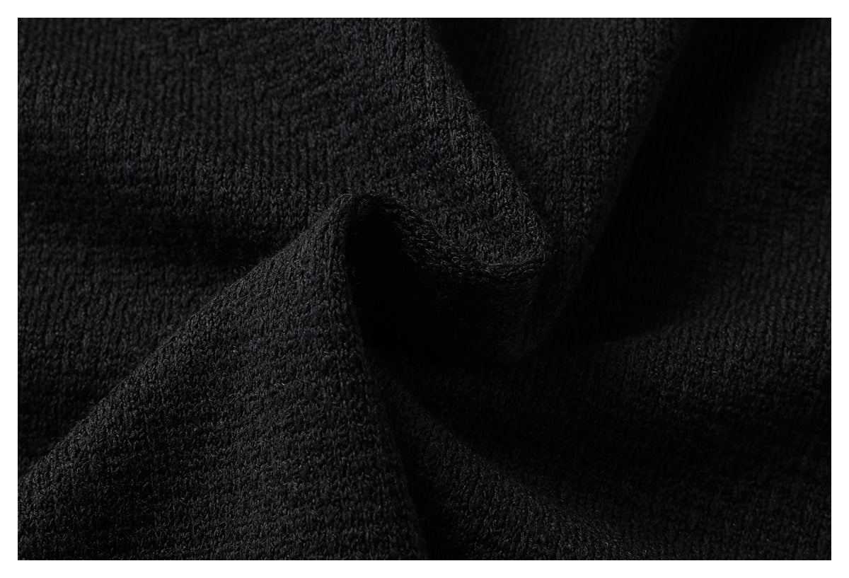 Close-up of black textured fabric gathered into a fold, showing its knit surface.