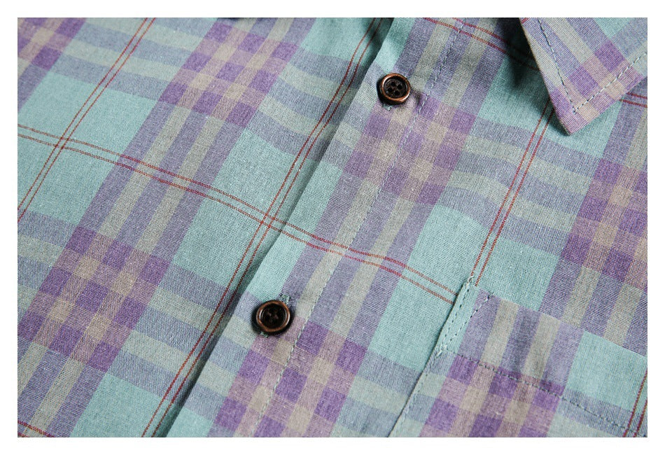 Close-up of the plaid shirt's front button placket, dark buttons and chest pocket.