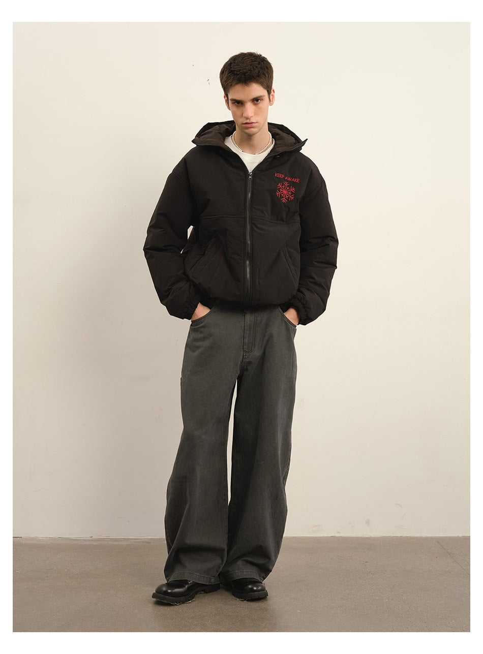 Full-length model wearing a black hooded zip jacket with red snowflake embroidery and loose gray jeans.