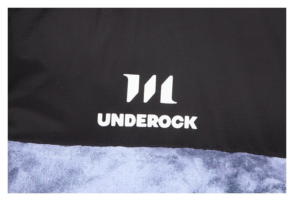 Close-up of the white UNDEROCK logo on the jacket's black panel above mottled blue-gray fabric.