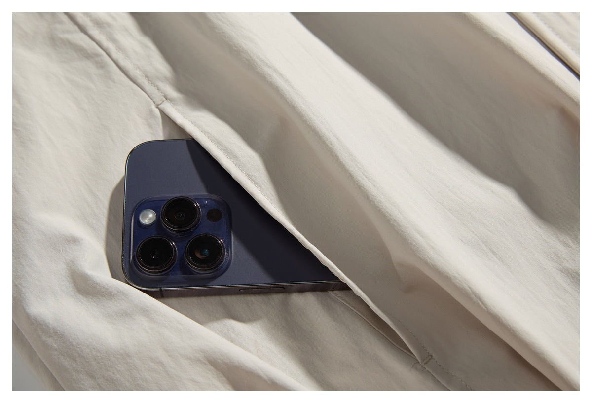 Close-up of an off-white garment pocket with a dark smartphone partly tucked inside.