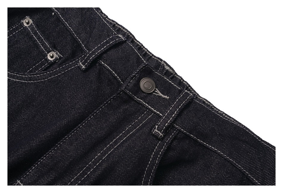 Close-up of the metal button, belt loop, and front pocket stitching on black denim jeans.