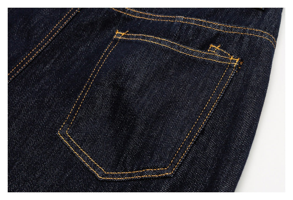 Close-up of a back pocket on dark indigo jeans, outlined with golden-orange double stitching.