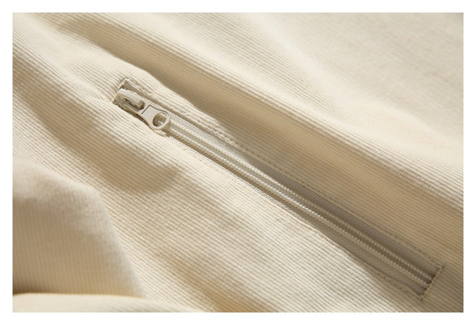 Close-up of a cream ribbed garment's zipper and seam.
