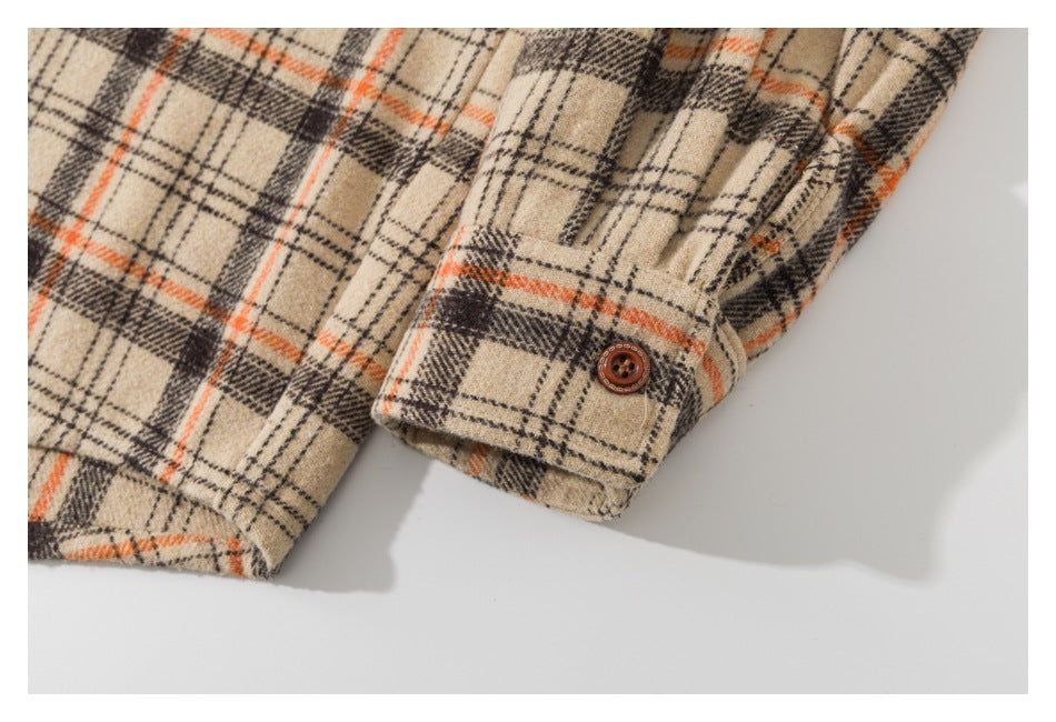 Close-up of a buttoned cuff on a beige shirt with orange and dark plaid lines.