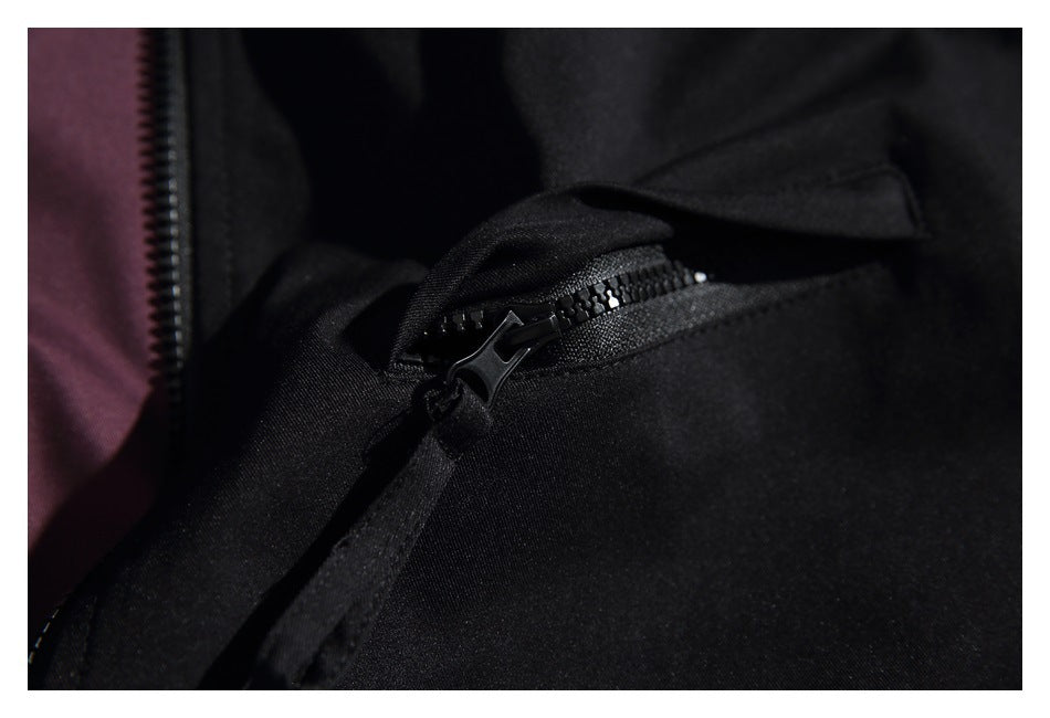 Close-up of a black garment's zipper pocket, with a glimpse of burgundy lining.