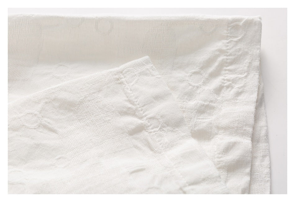 Close-up of layered white textured fabric with a stitched edge and seam.