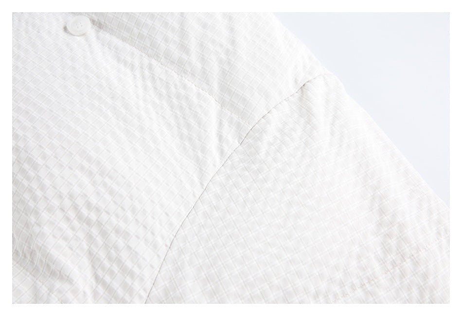 Close-up of the white quilted jacket sleeve and shoulder seam.