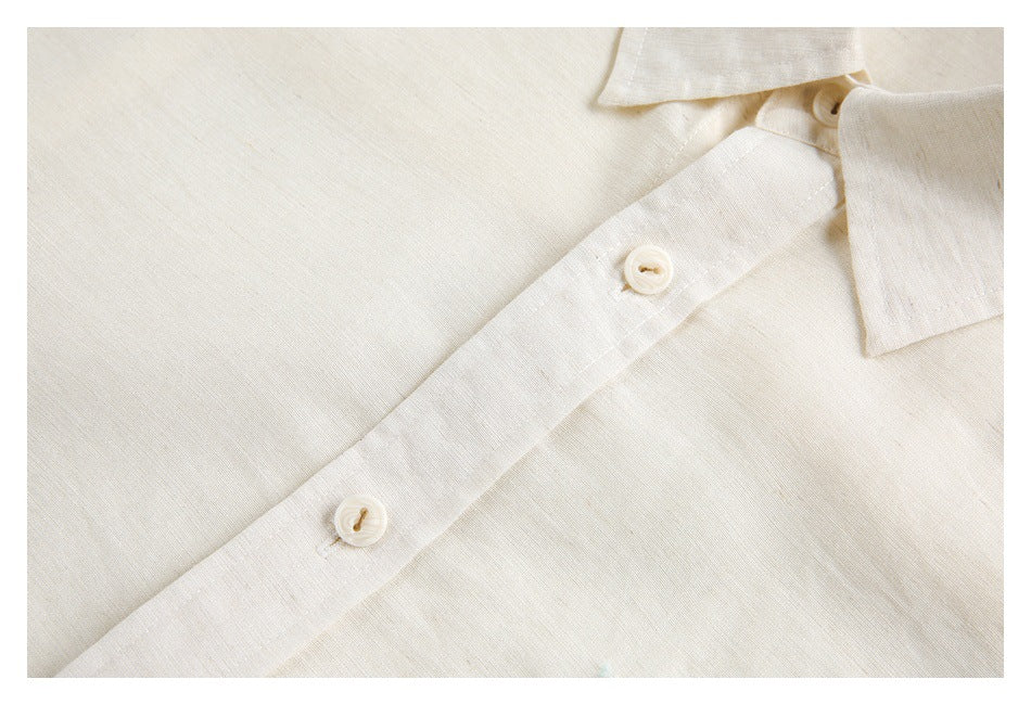 Close-up of an ivory shirt's front placket, two buttons, and collar edge.