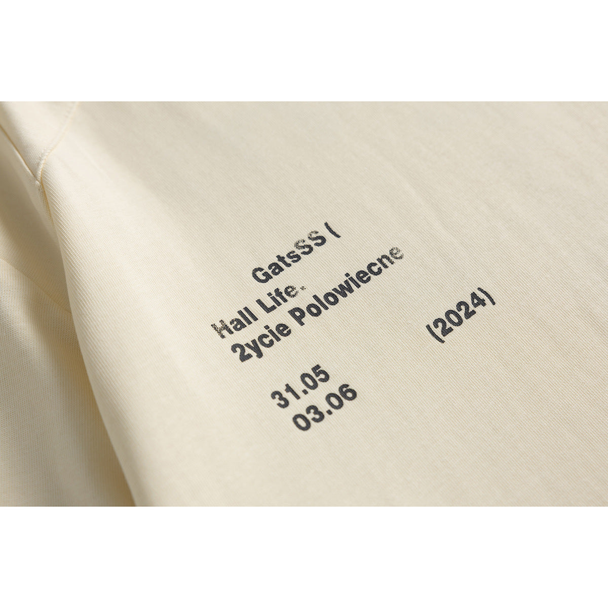 Close-up of small black text printed on the chest of a cream T-shirt.
