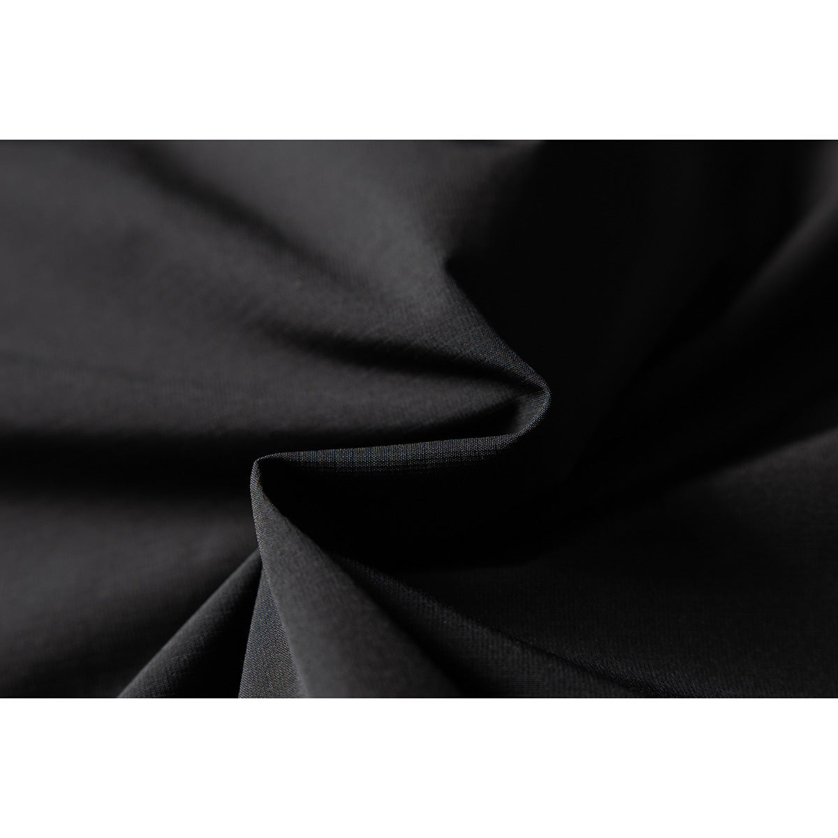 Close-up of folded black jacket fabric showing its fine woven texture.