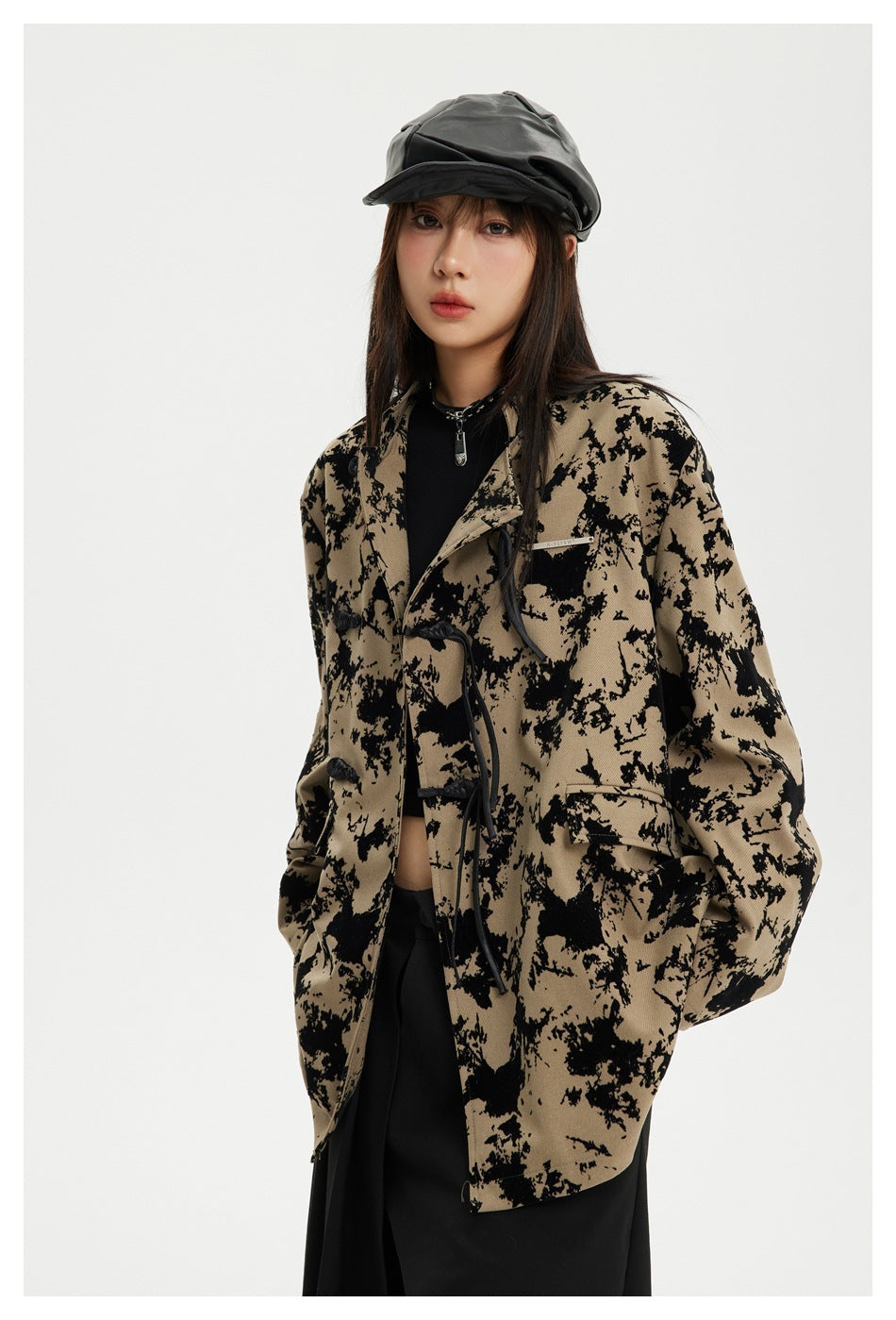 Model wearing an oversized tan jacket with an irregular black pattern, toggle closures and flap pockets.