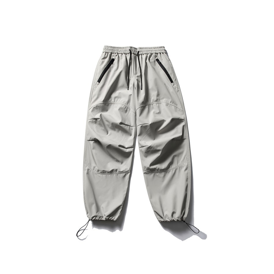 Light gray drawstring pants flat lay with zippered pockets, curved knee seams and drawcord hems
