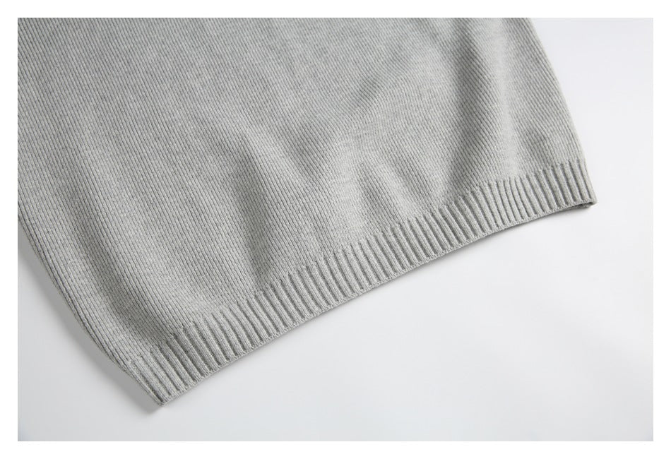 Close-up of the ribbed hem on a light gray knit garment against a white background.