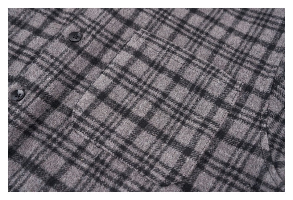 Close-up of the gray and black plaid shirt front with black buttons and a stitched chest pocket.