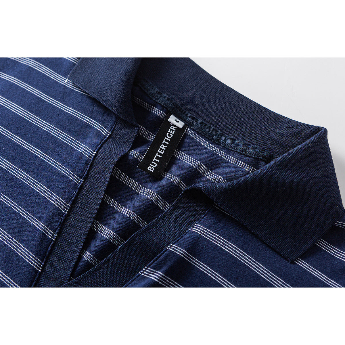 Close-up of a navy striped polo collar and placket, with a visible sewn-in neck label.