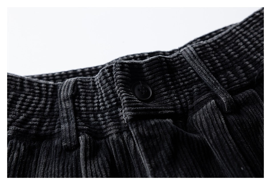 Close-up of the black ribbed trousers' buttoned waistband and belt loops.