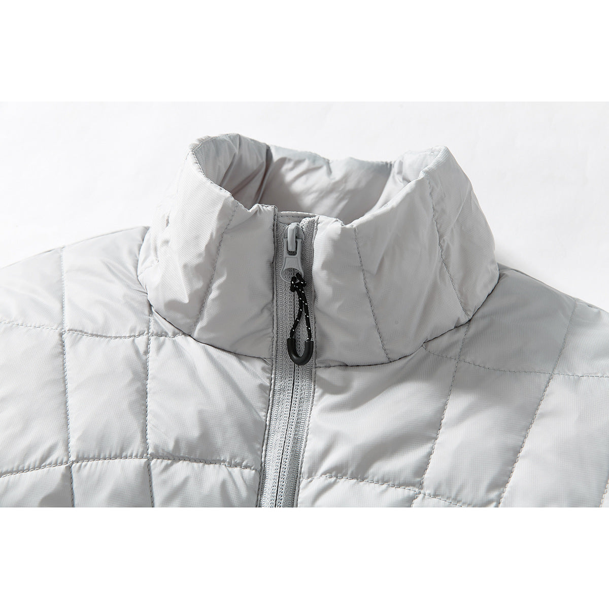 Close-up of a light gray quilted jacket’s high stand collar and front zipper with a black pull cord.