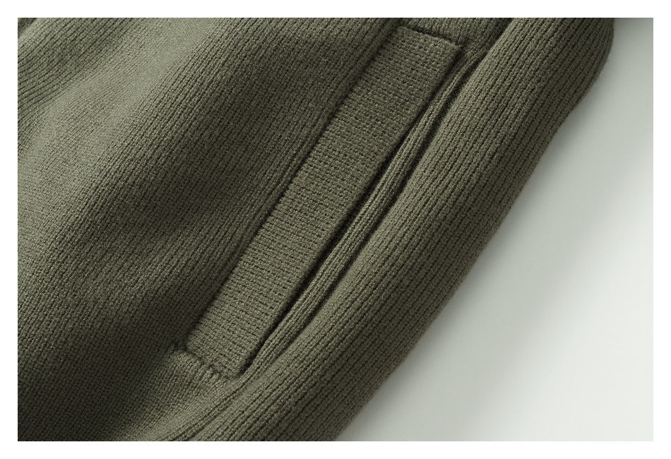 Close-up of a welt pocket and ribbed edge on an olive-gray knit garment.