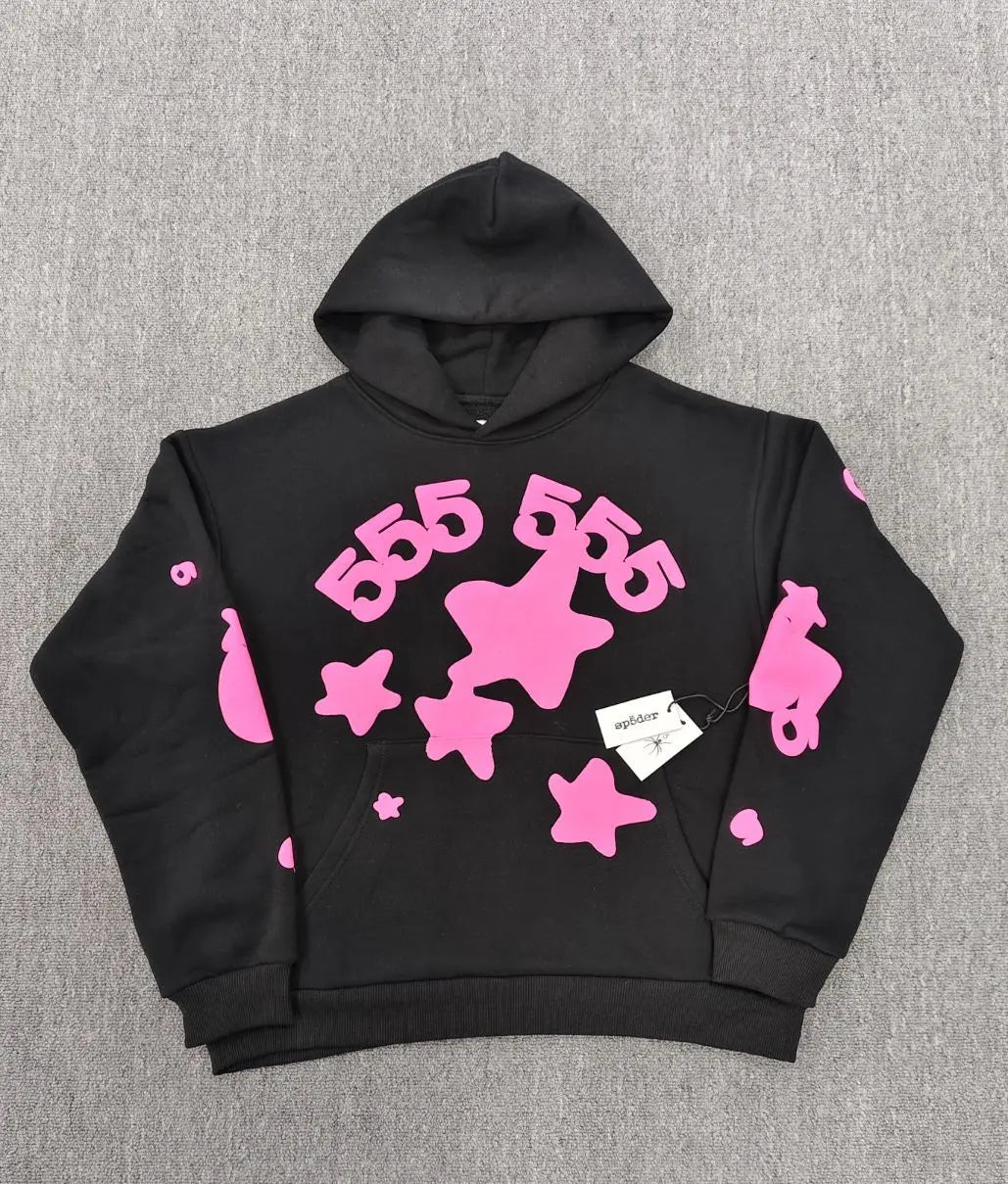 Sp5der 555 black hoodie with pink star print and arched 555 graphic lettering laid flat on grey surface