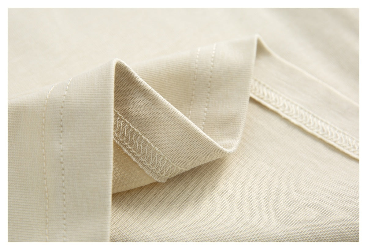 Inside close-up of ivory shirt fabric, showing folded seam edges and overlock stitching.