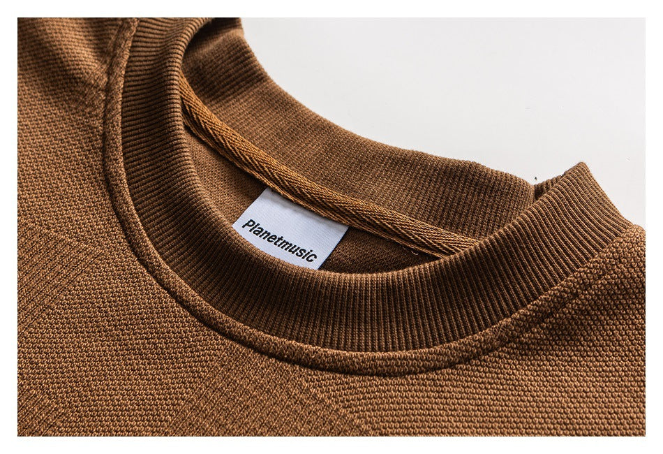 Close-up of a brown knit crew neckline with ribbed trim and a white sewn-in label.
