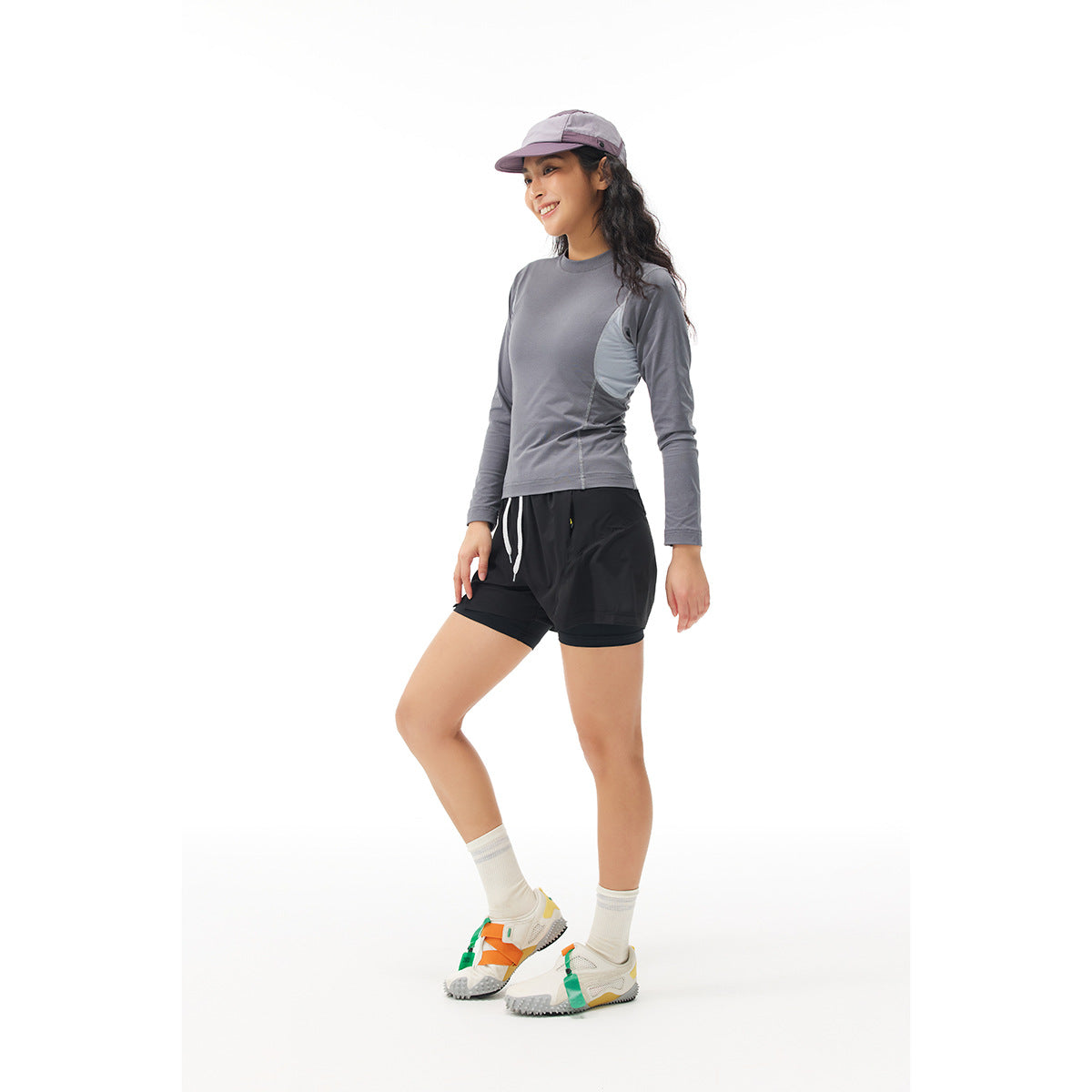 Model wearing a gray long-sleeve top with pale blue side panels and black layered shorts.