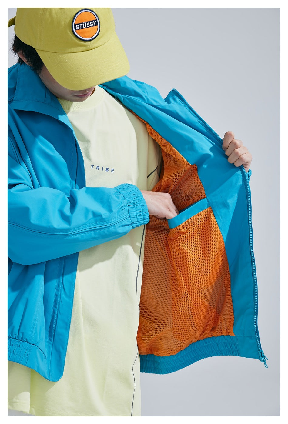Close view of the turquoise jacket opened to show orange mesh lining and an interior pocket.