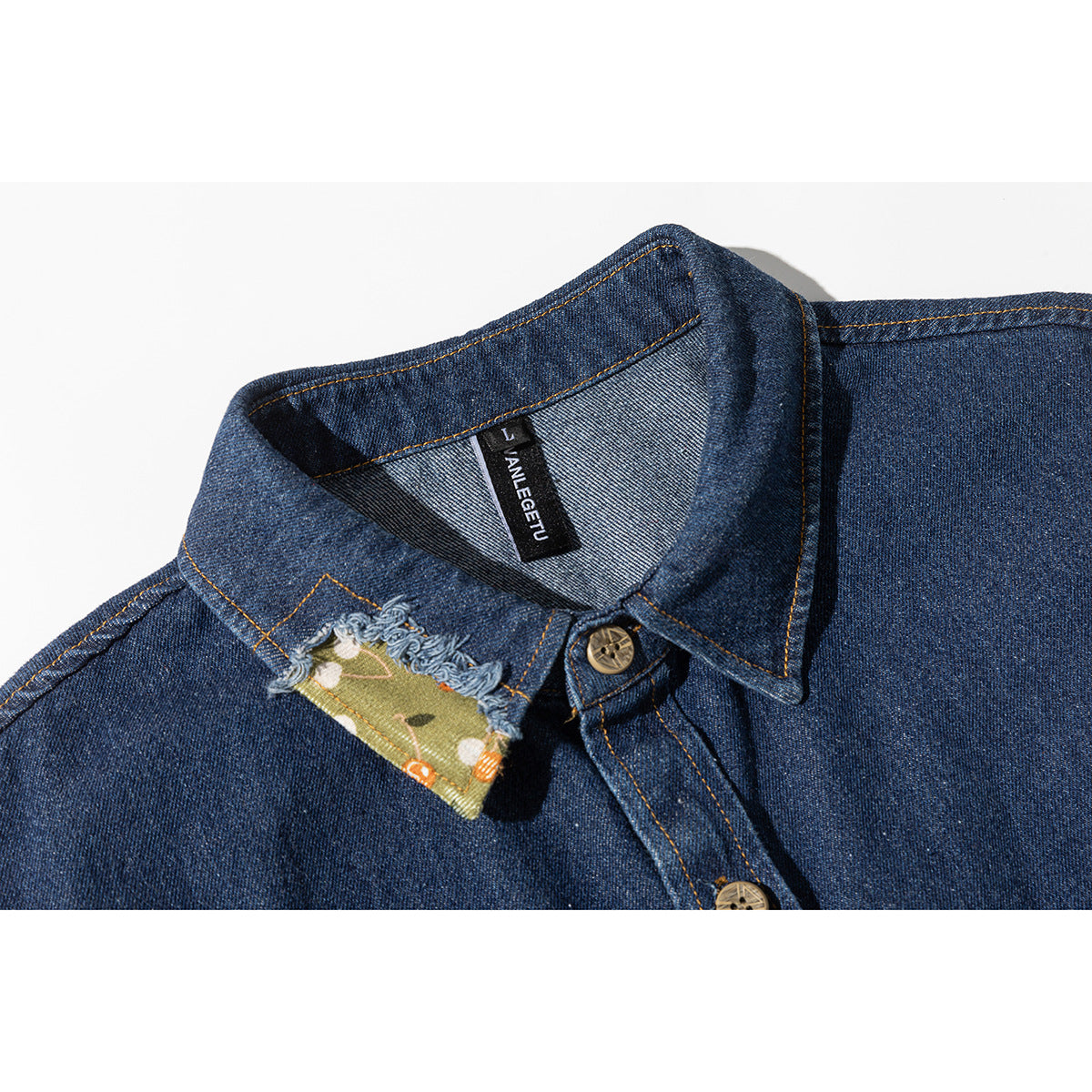 Close-up of a dark blue denim shirt collar with a frayed green floral patch and a visible black neck label.