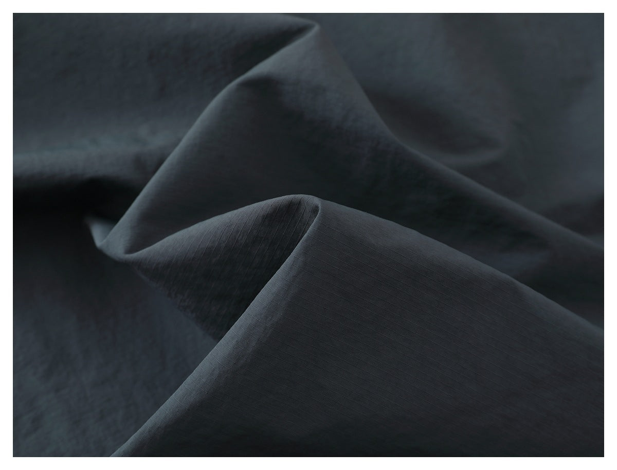 Close-up of dark charcoal fabric folded to show its fine grid-like texture.