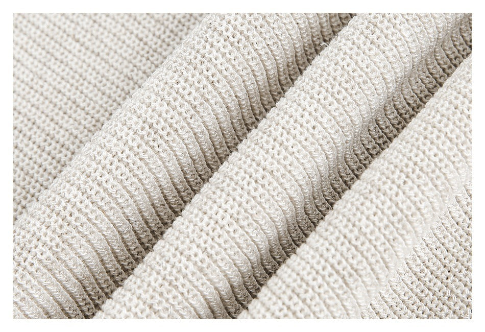 Close-up of cream knit fabric with raised ribbed folds and a looped texture.